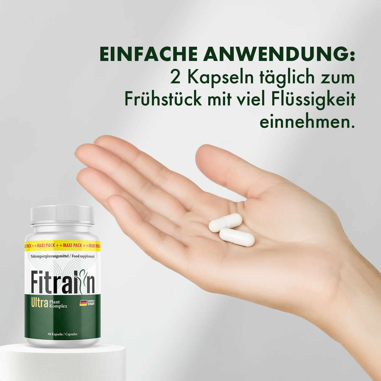 Hand mit zwei weißen Kapseln neben Fitralin Ultra Plant Komplex Dose und Anwendungshinweis