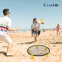 Thumbnail for Schwarzes rundes Netz mit gelben Halterungen im Sand, mehrere Personen spielen am Meer