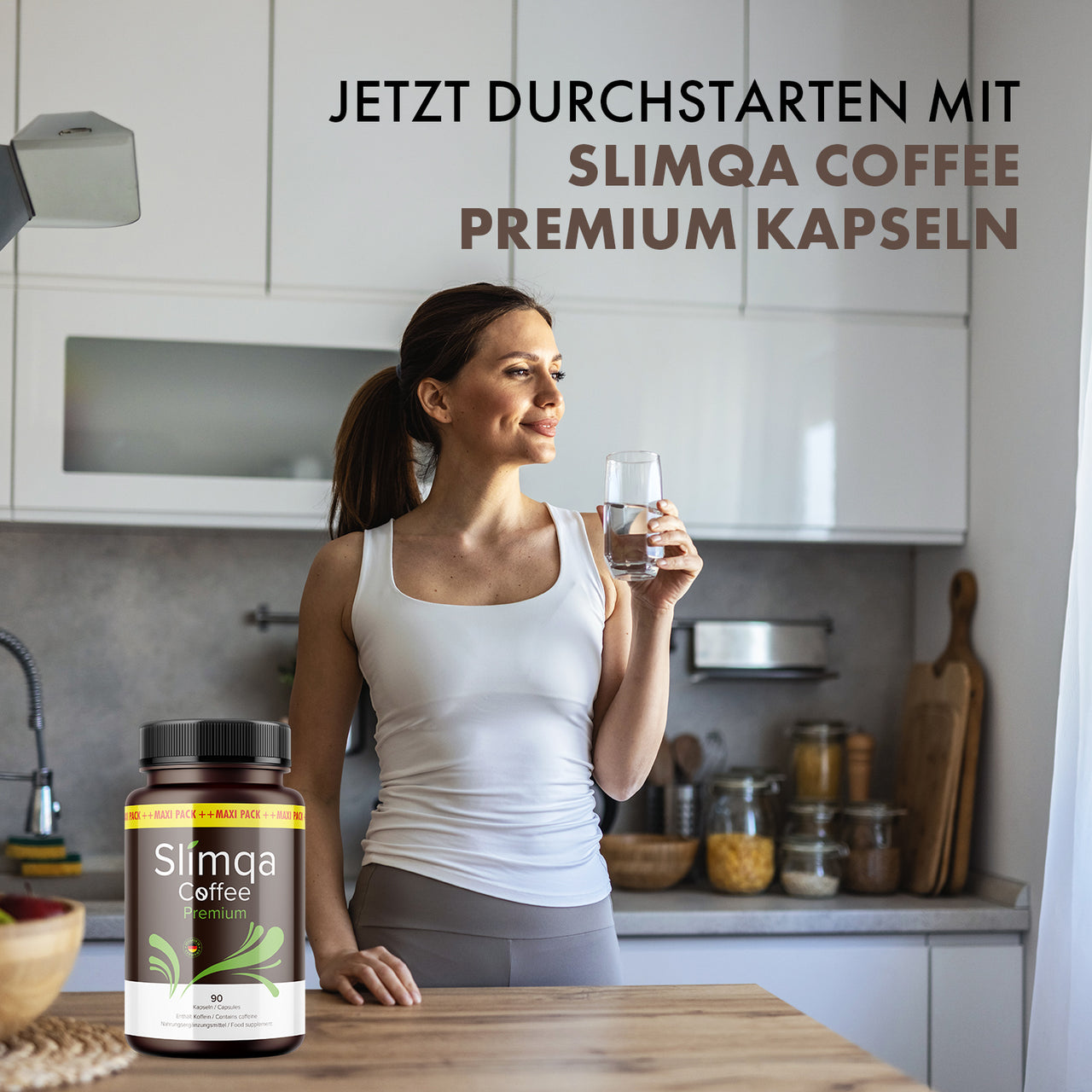 Frau hält ein Wasserglas in einer Küche neben einer Dose Slimqa Coffee Premium Kapseln auf dem Tisch